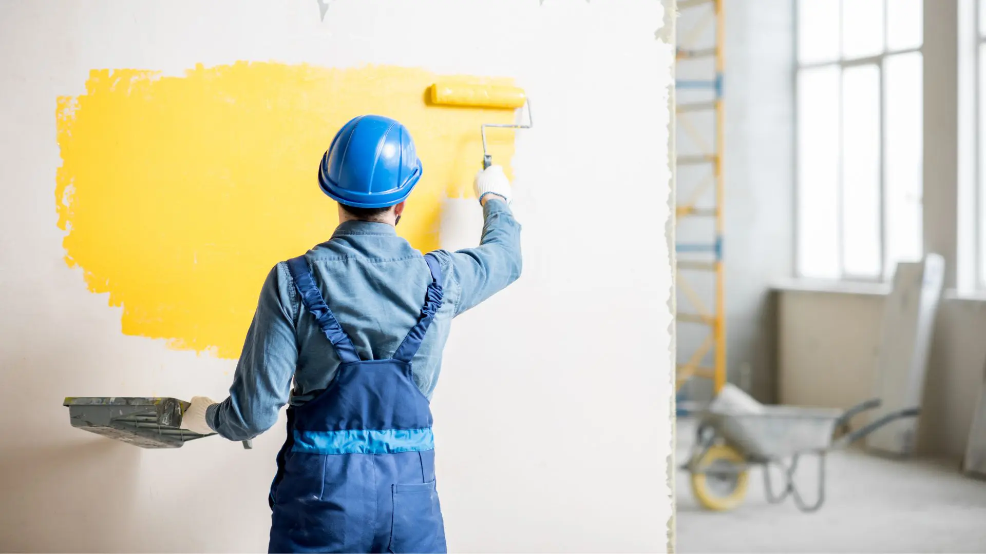 Worker painting wall yellow